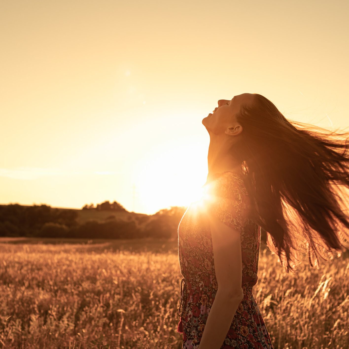 Woman in a Meadow at sunset looking up to the sky feeling joyfull